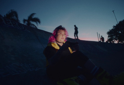 a woman with pink hair sitting on a skateboard