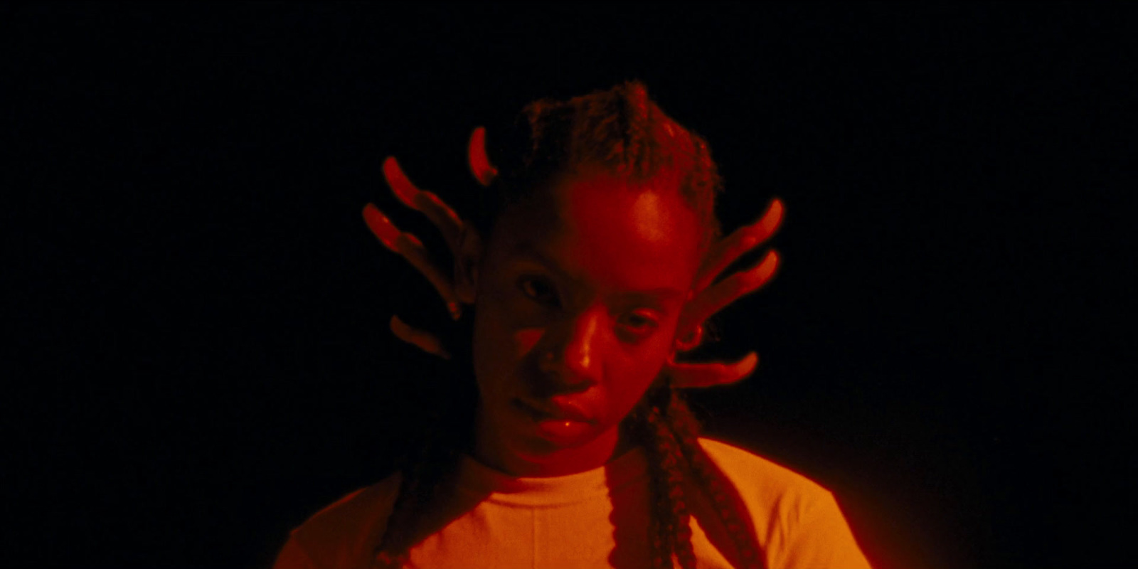 a man with dreadlocks standing in the dark