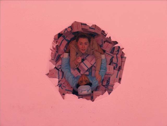 a woman laying on the ground through a hole in a wall