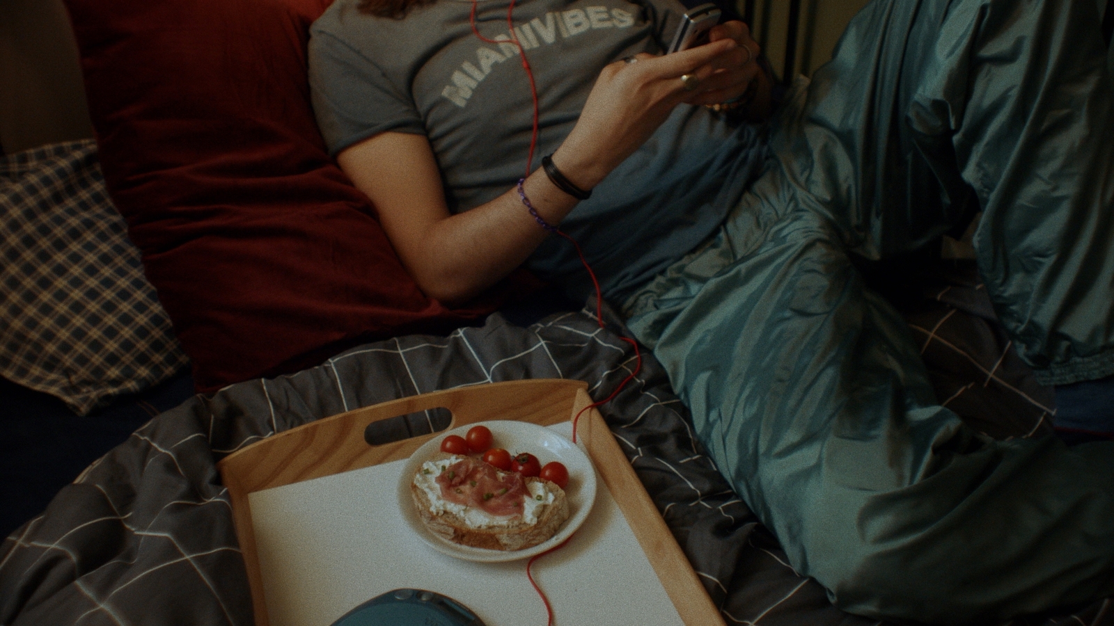 a person sitting on a bed with a plate of food