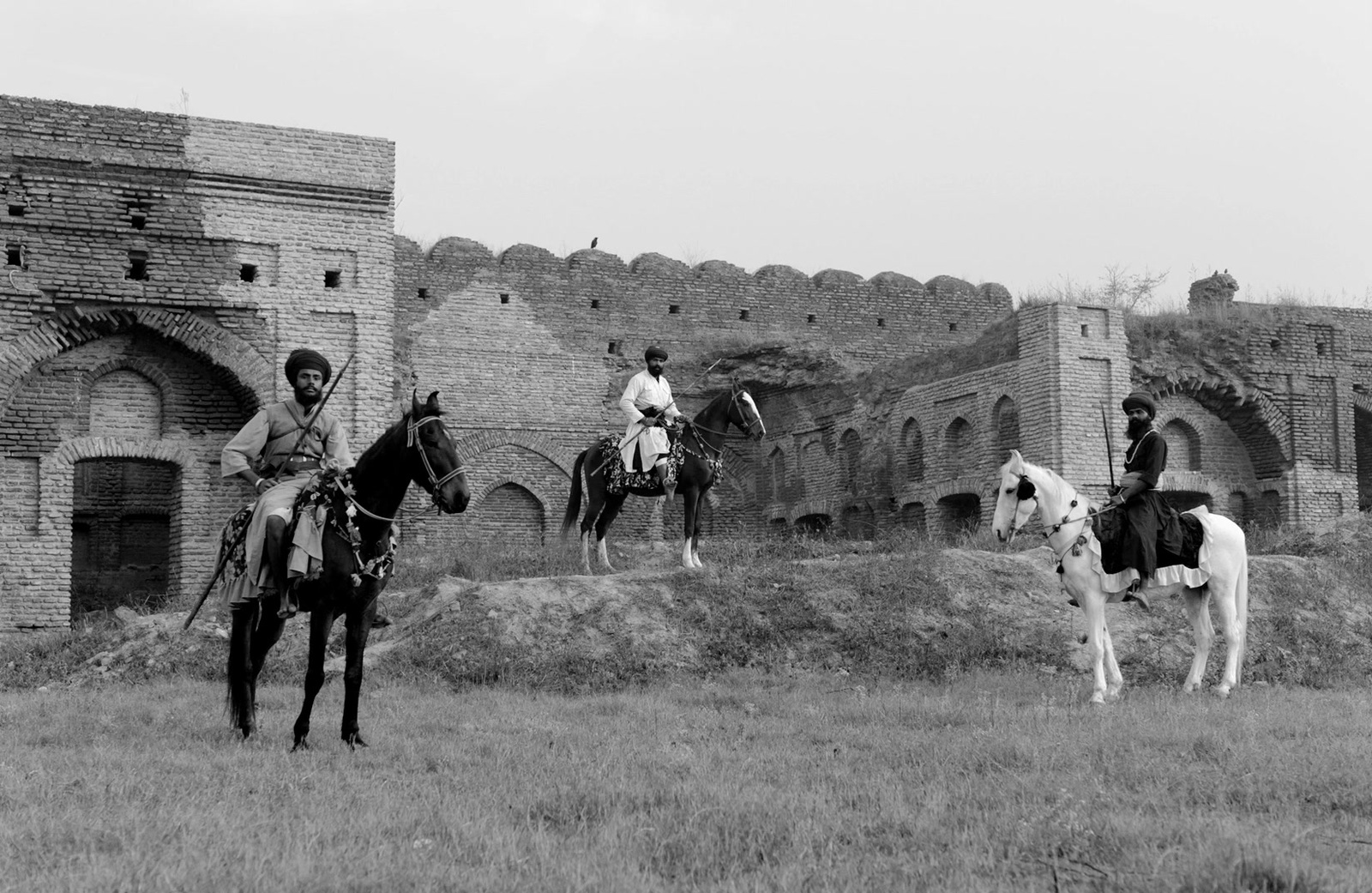 a black and white photo of two men on horses