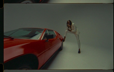 a woman leaning on a red car in front of a white background