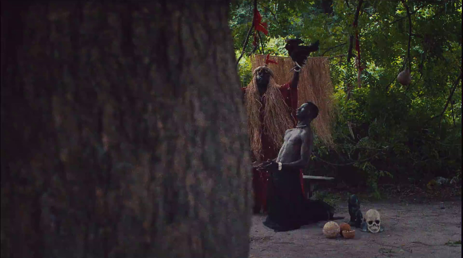 a man with a knife standing next to a tree