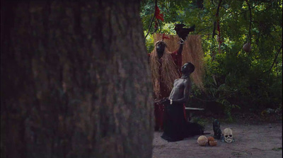 a man with a knife standing next to a tree