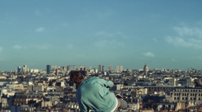 a man sitting on a ledge overlooking a city