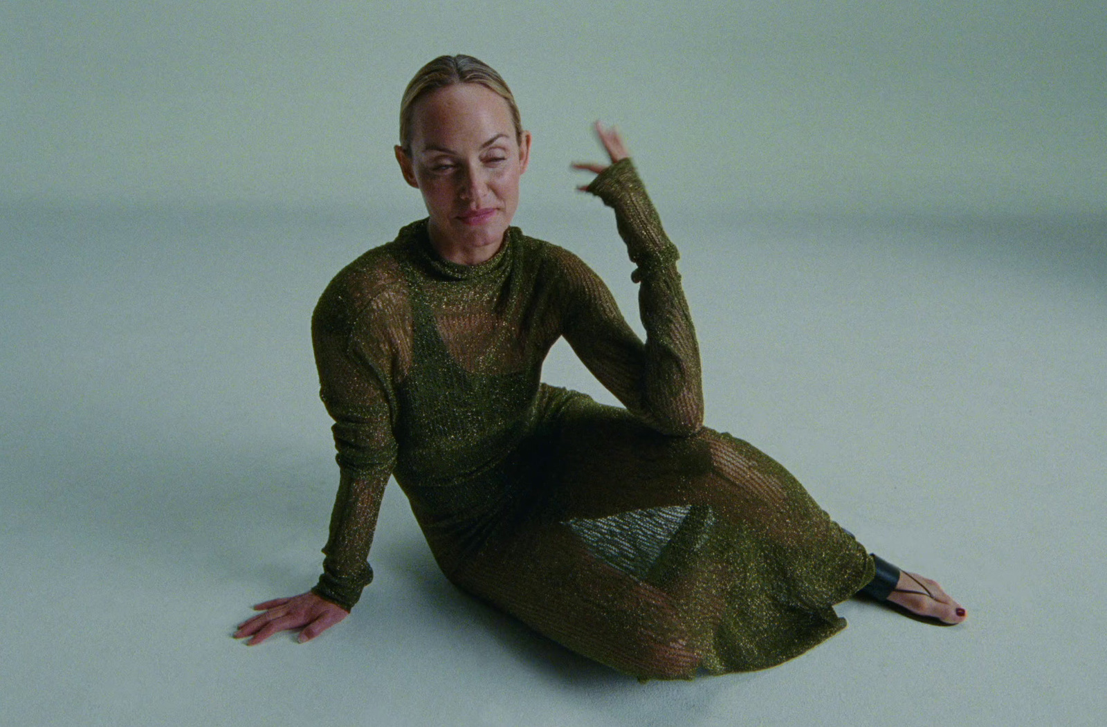 a woman is sitting on the floor with her hands in the air