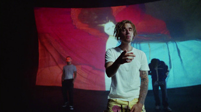 a man with dreadlocks standing in front of a screen