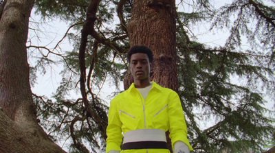 a man in a yellow jacket standing in front of a tree