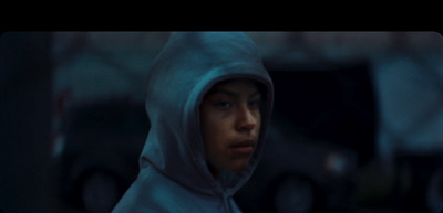 a man in a hoodie stares into the distance