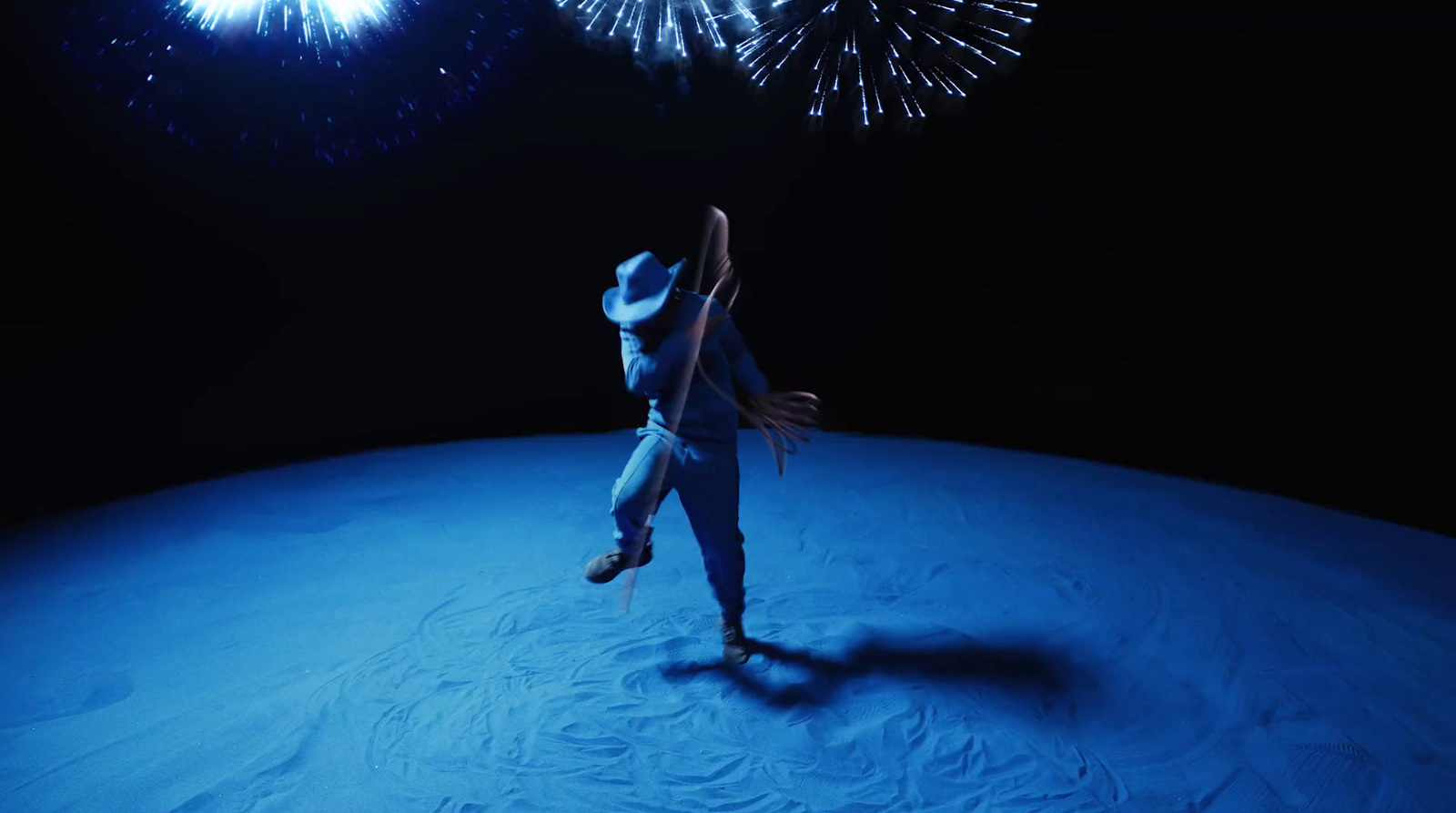 a person in a white hat is dancing with fireworks in the background