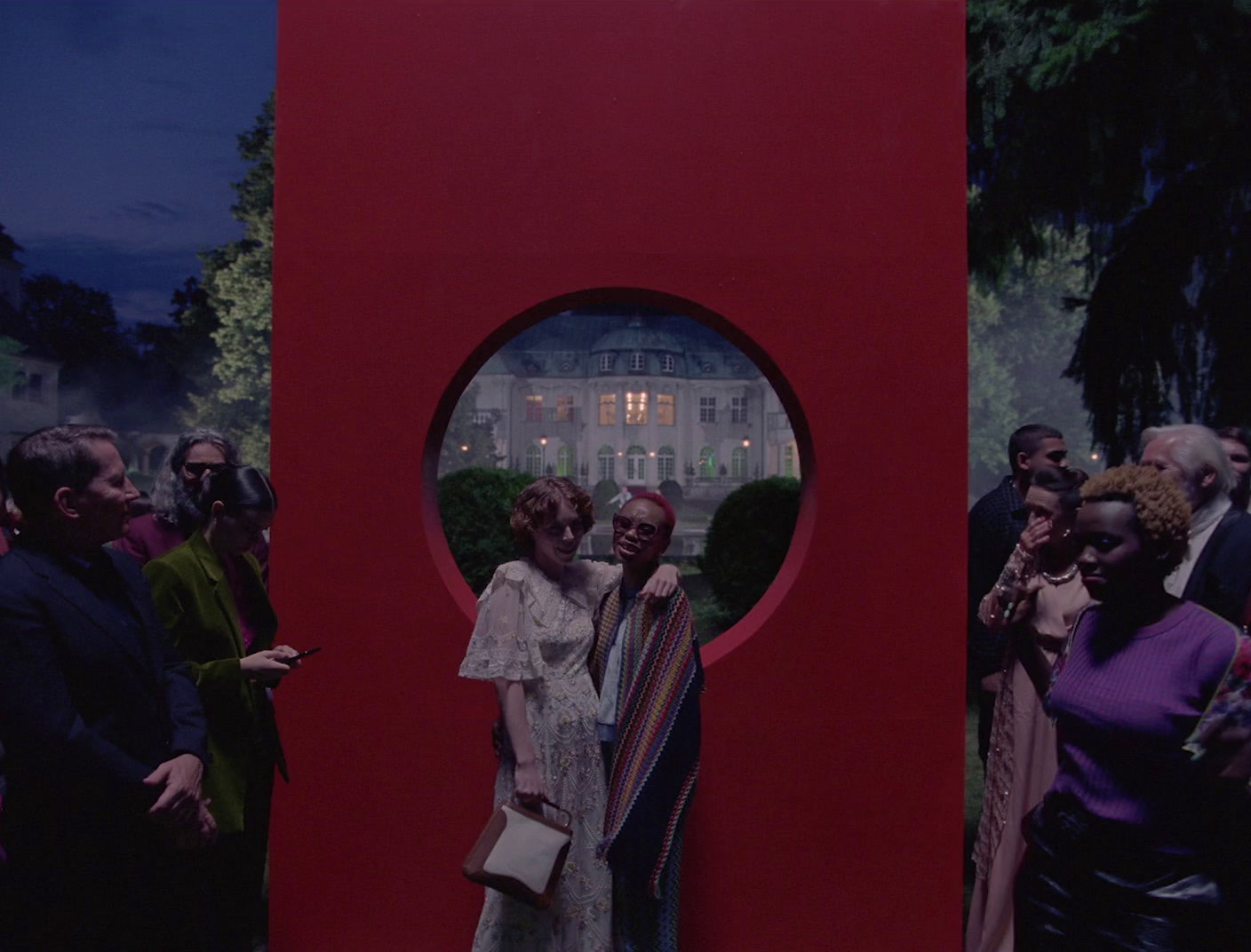 a group of people standing around a red sculpture