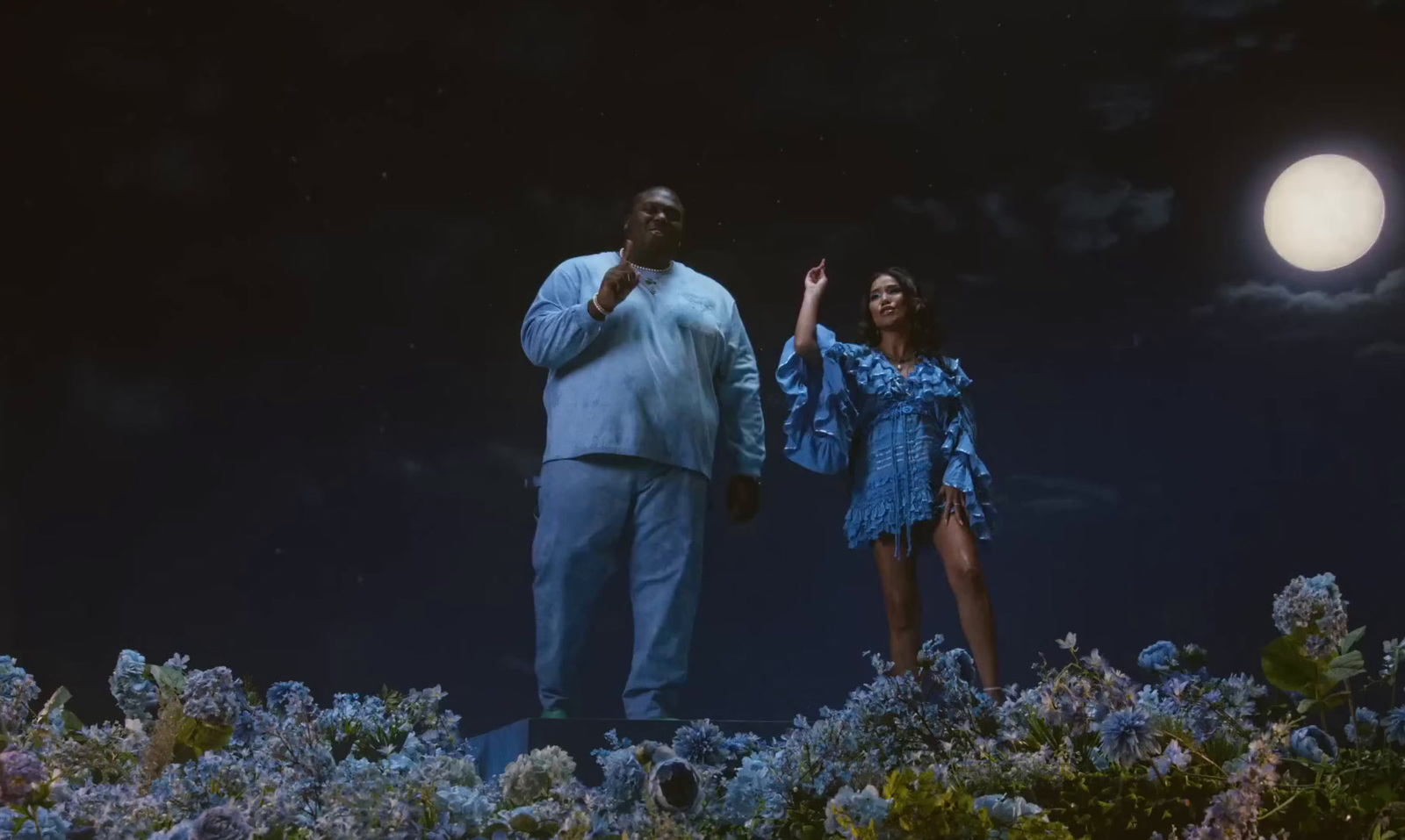 a man and a woman standing on a hill at night