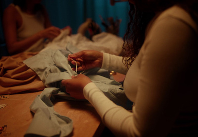 a woman is sewing on a piece of cloth