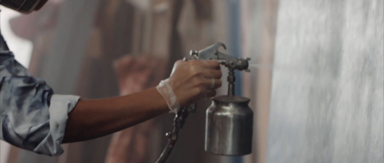 a person spraying paint on a wall with a spray gun