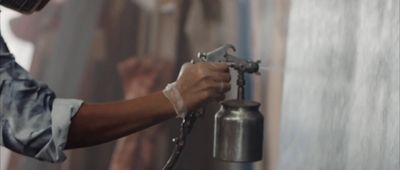 a person spraying paint on a wall with a spray gun