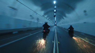 a couple of people riding motorcycles down a tunnel