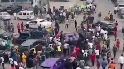 a crowd of people standing around a car in a parking lot