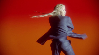 a woman in a blue suit is standing in front of a red background