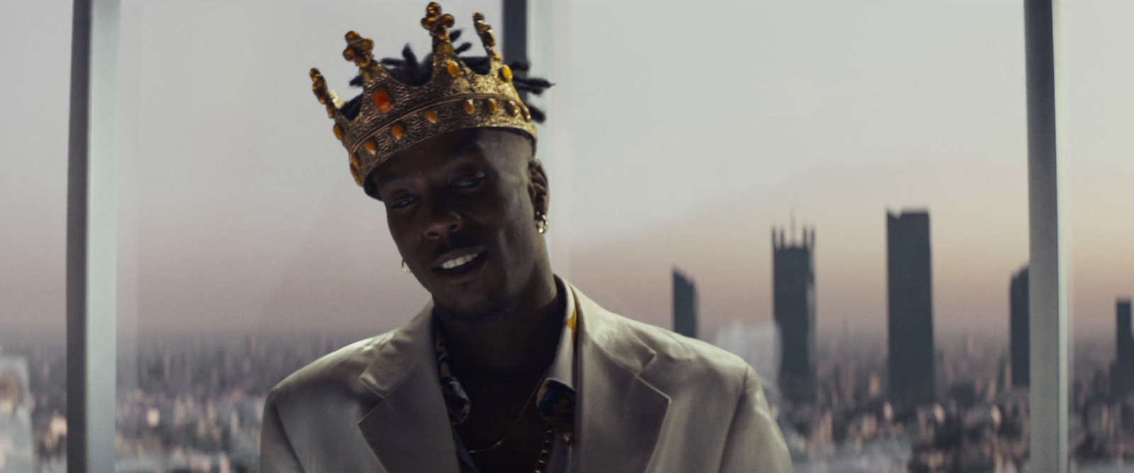 a man with a crown on his head standing in front of a window