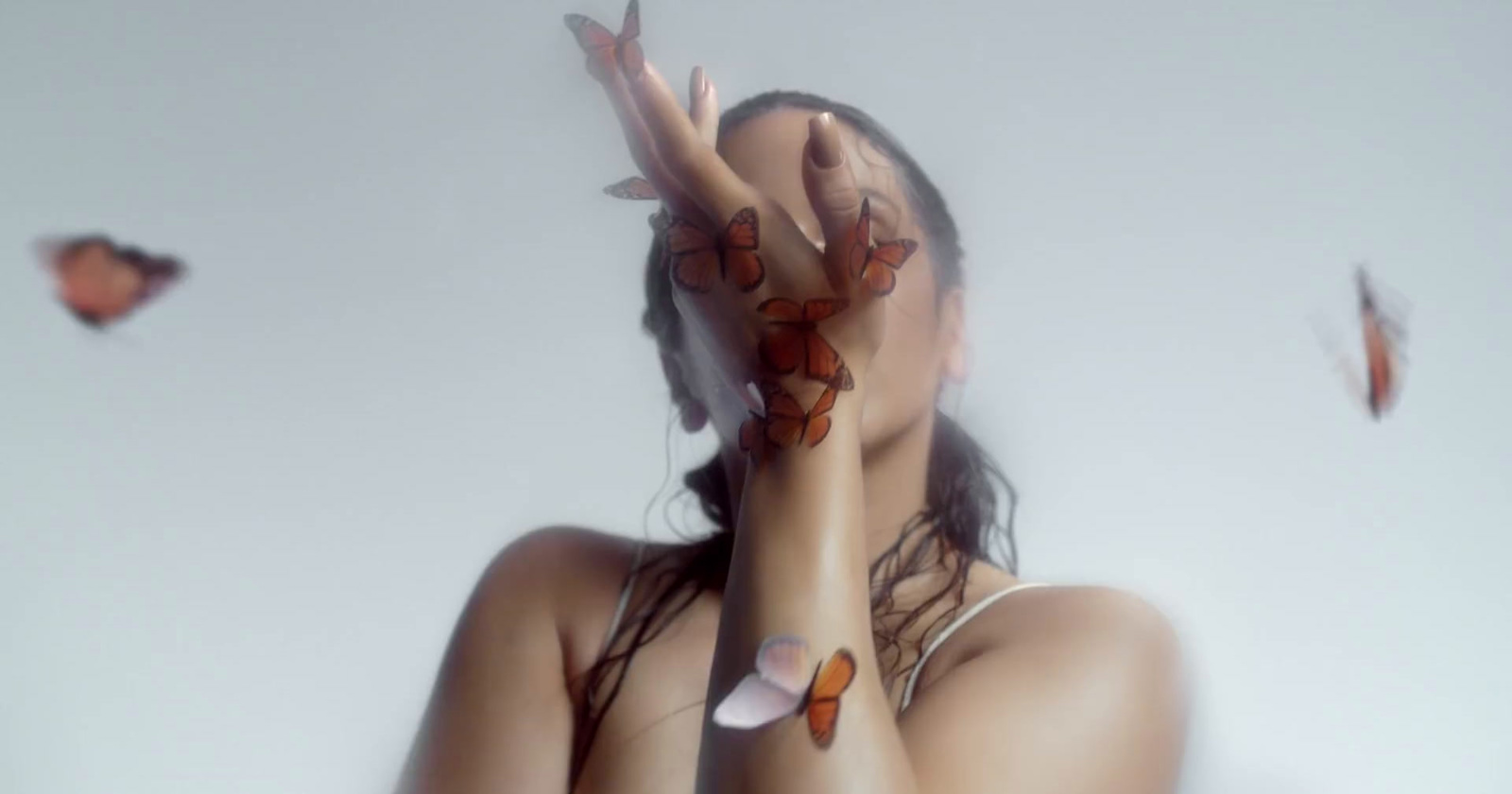 a woman with butterflies on her arm covering her face