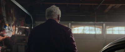 a man standing next to a car in a garage