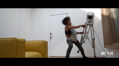 a woman standing on top of a ladder next to a yellow chair