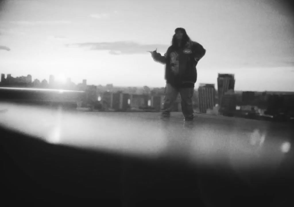 a man standing on top of a roof next to a tall building