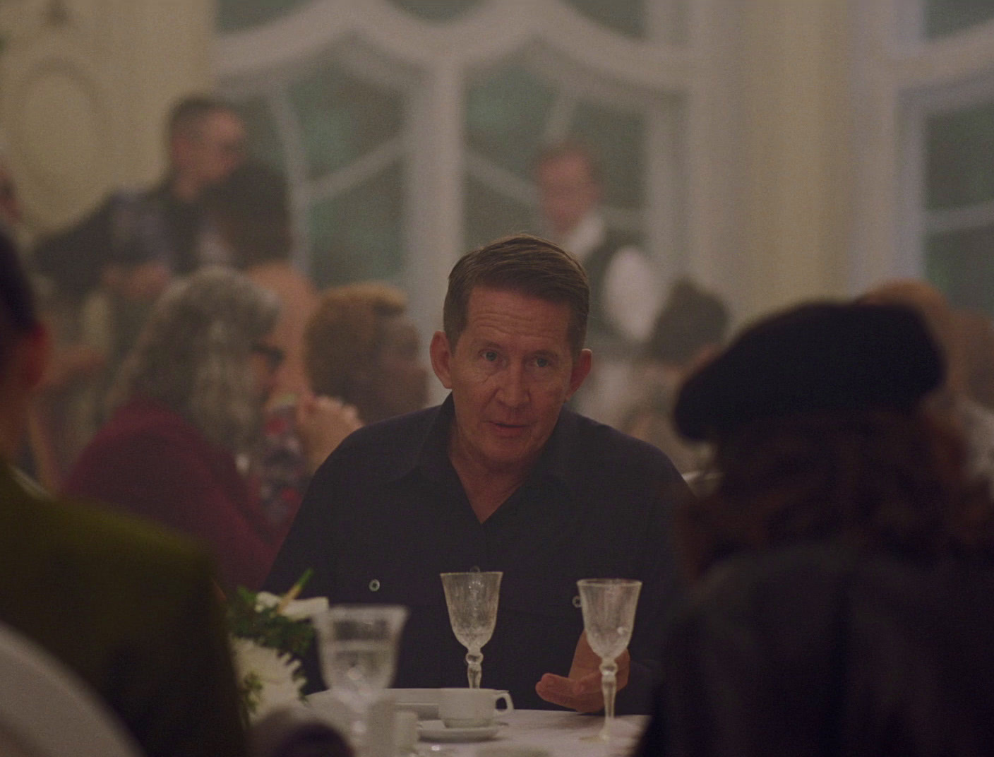 a man sitting at a table with wine glasses