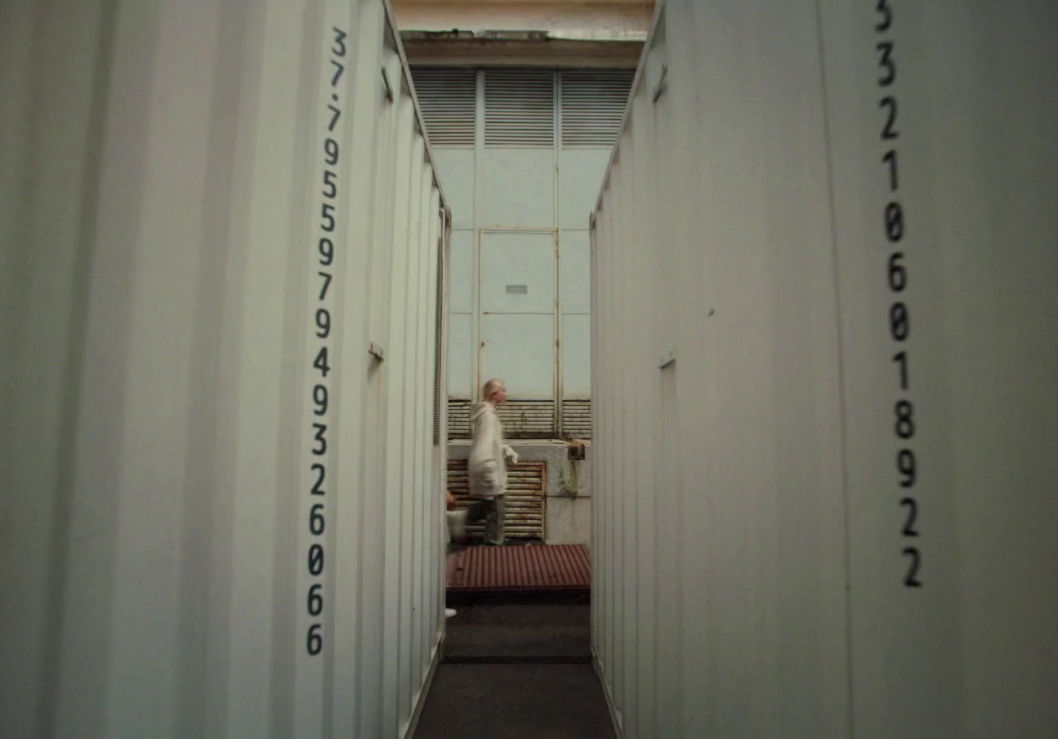 a narrow hallway between two white shipping containers