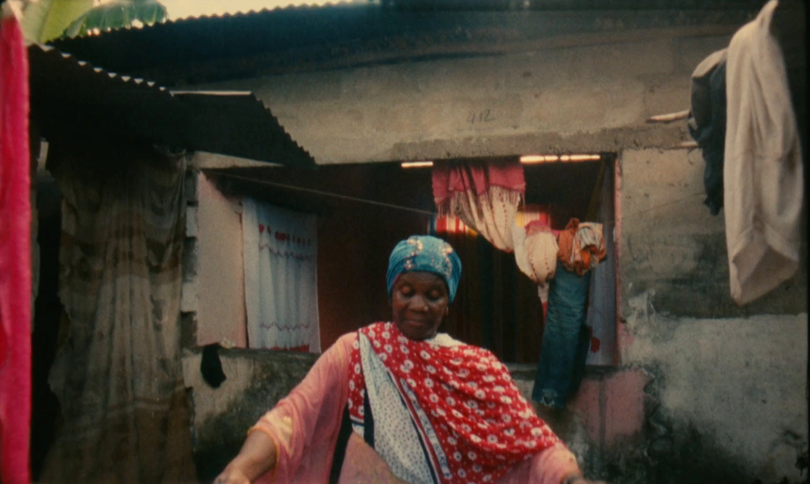 a woman in a red and white dress standing in front of a house