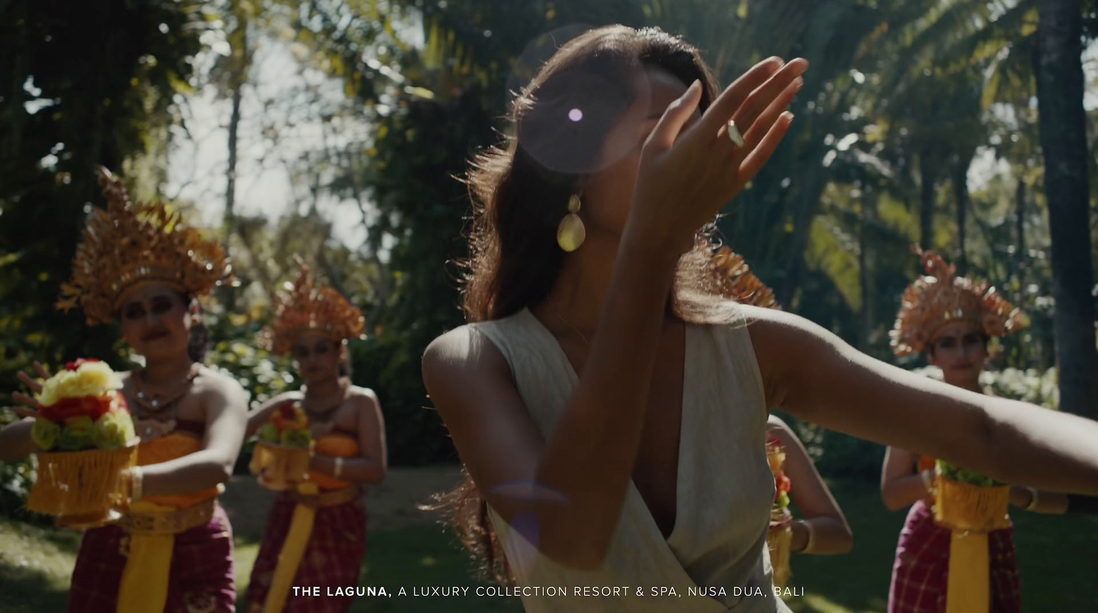 a woman in a white dress is holding her hands up