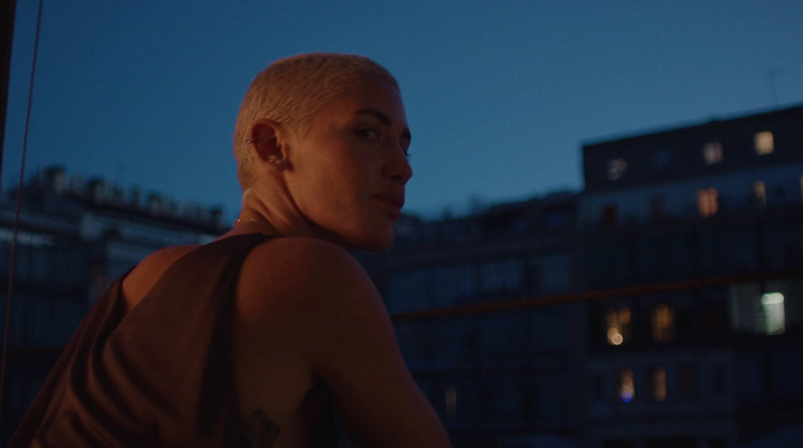 a woman with white hair and a shaved head standing in front of a building