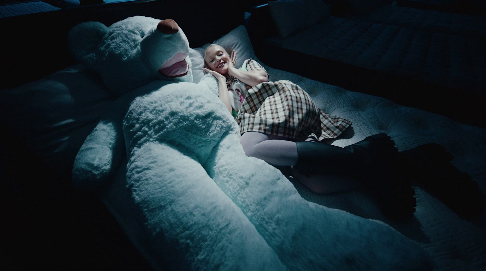 a woman laying on a bed with a giant teddy bear