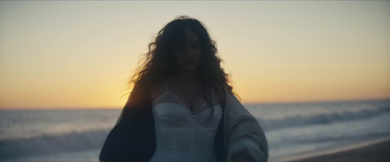 a woman standing on a beach at sunset