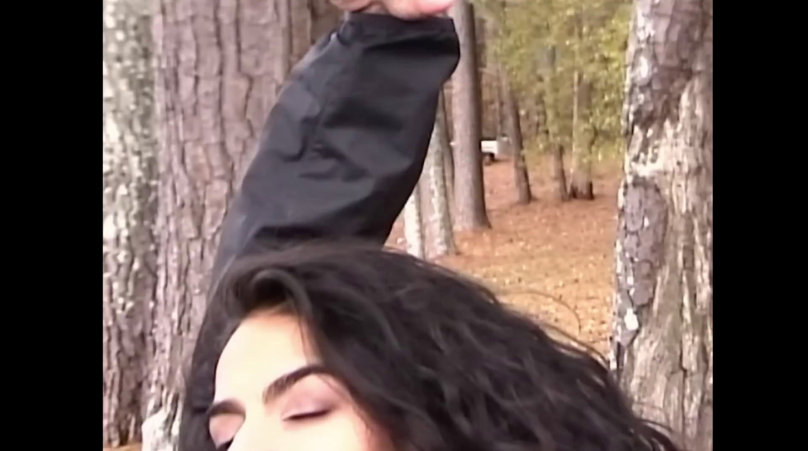 a woman with long hair standing in the woods