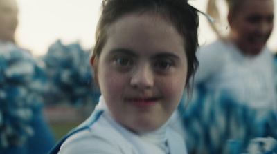 a young girl with a ponytail standing in front of a group of other people