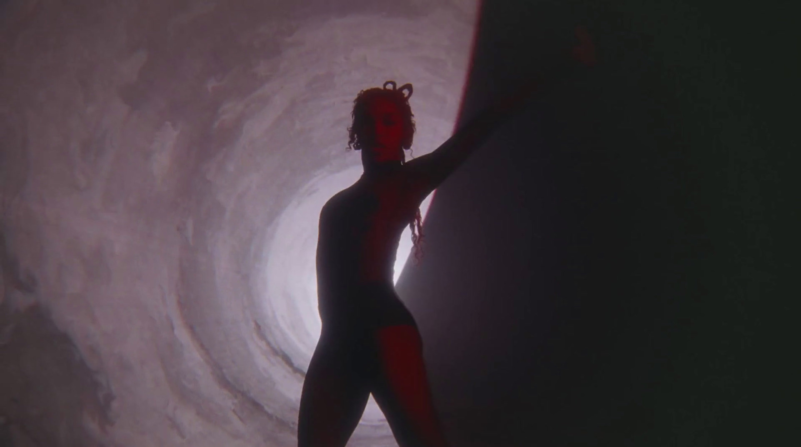 a woman in a bodysuit standing in a tunnel