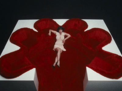 a woman in a white dress is laying on a large red object