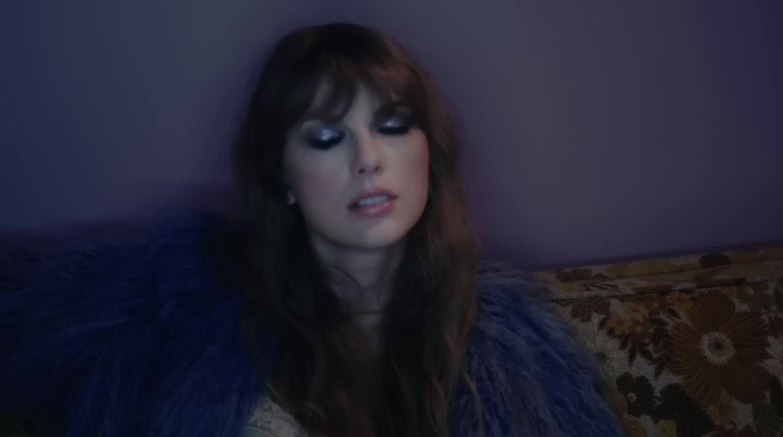 a woman sitting on a couch wearing a fur coat