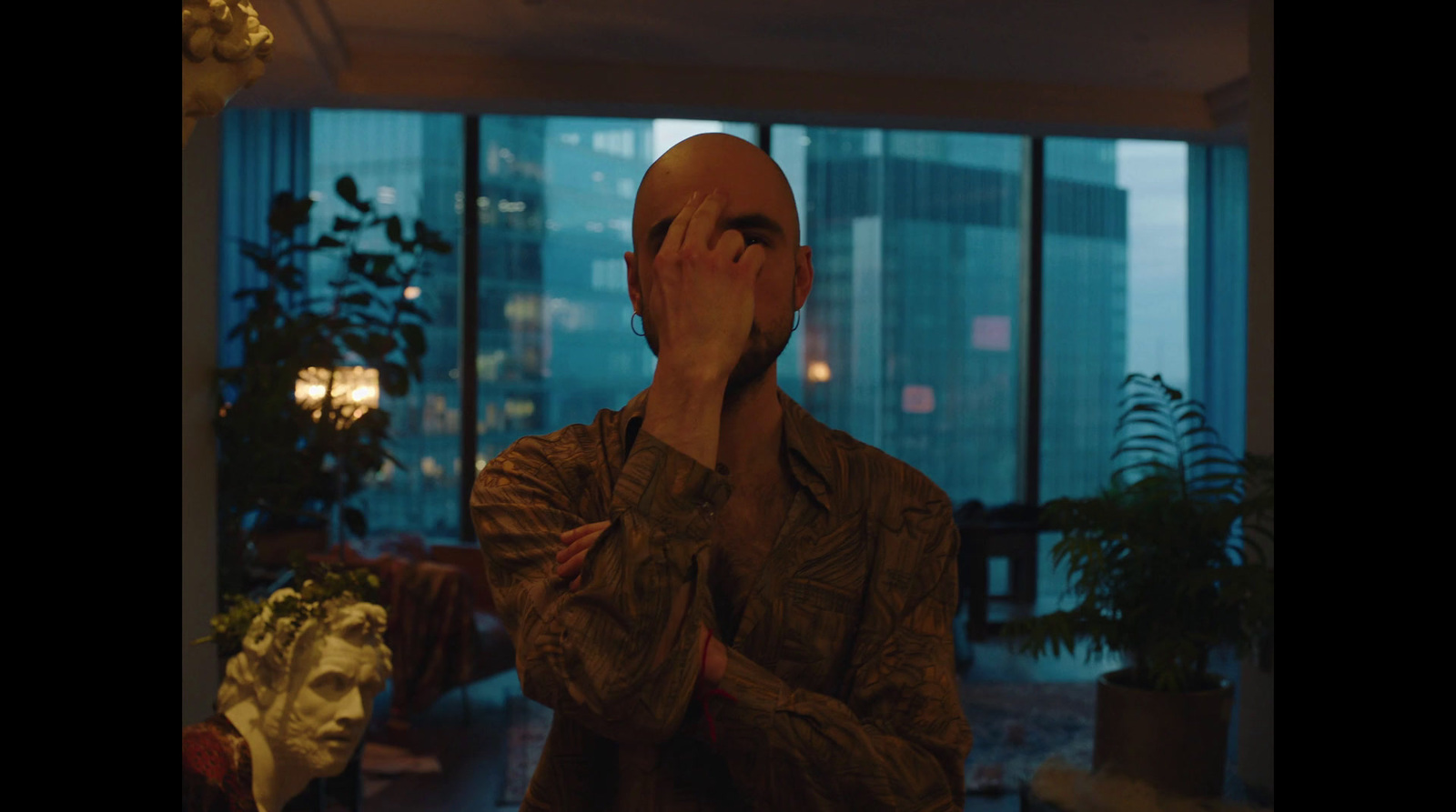 a man standing in front of a window covering his eyes