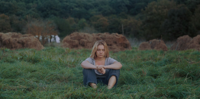 a woman sitting on the ground in a field