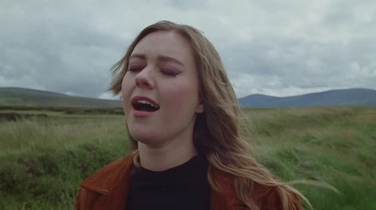 a woman standing in a field with her eyes closed