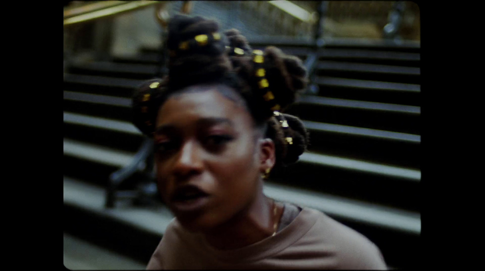 a woman with braids on her head standing in front of a set of stairs