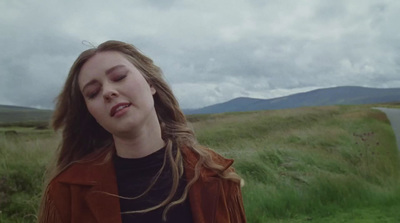 a woman standing in a field with her eyes closed