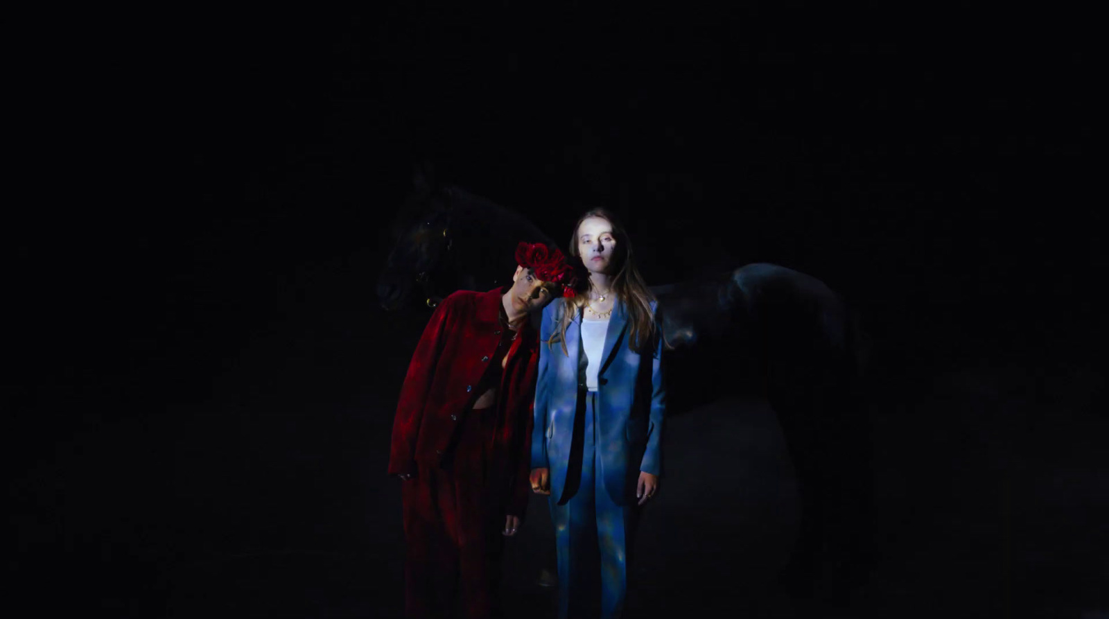 a woman standing next to a horse in the dark