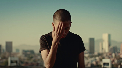 a man standing in front of a city skyline holding his hand to his face