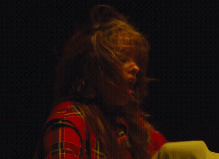 a woman with long hair standing in front of a table