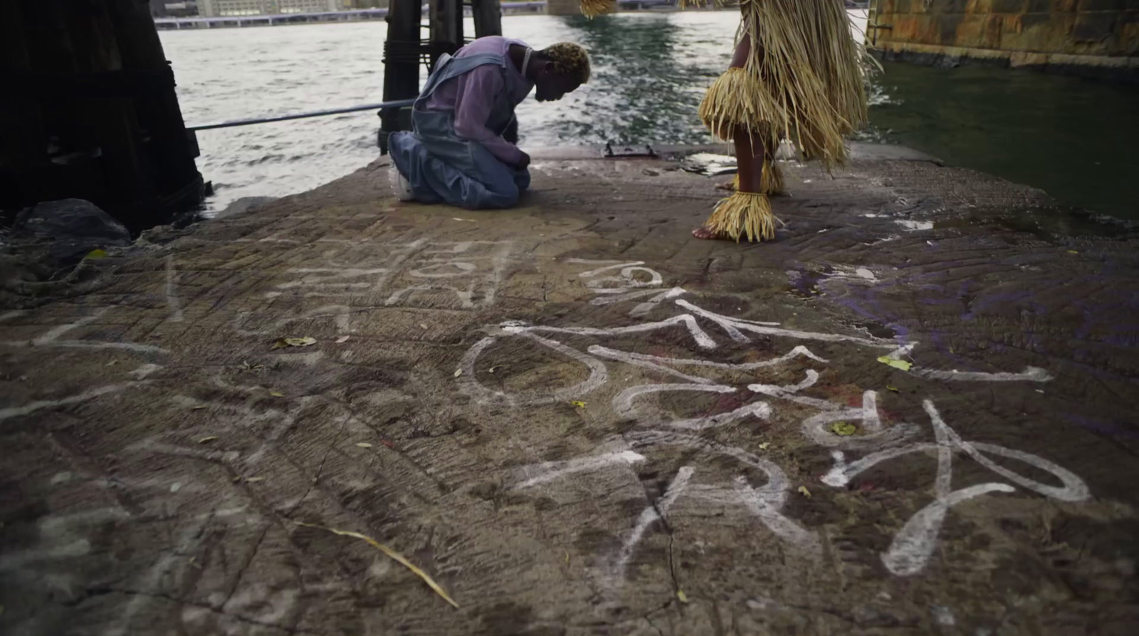 a man is writing on the ground next to a river