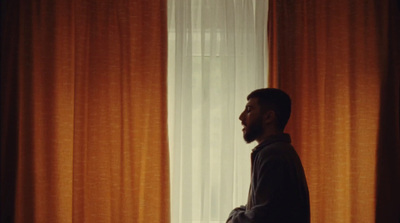 a man standing in front of a window with orange curtains