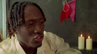 a man with dreadlocks sitting in front of a candle